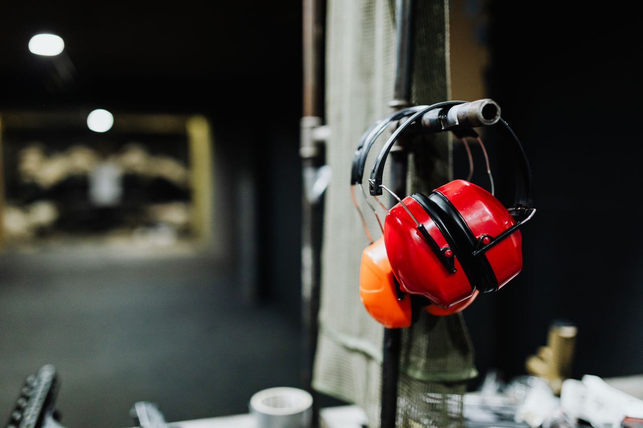 Red ear muffs hanging at an indoor shooting range, offering essential safety gear.